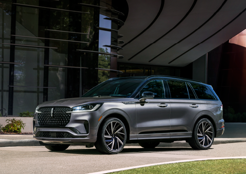 A gray 2025 Lincoln Aviator® SUV is parked outside a modern building showcasing the driver’s side of the vehicle. | Parks Lincoln of Wesley Chapel in Wesley Chapel FL