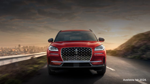 A 2025 red Lincoln Corsair® SUV is being driven down a road at sunset. | Parks Lincoln of Wesley Chapel in Wesley Chapel FL
