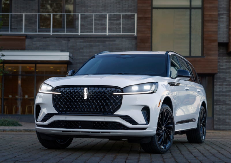 A 2026 Lincoln Aviator® Reserve model is shown with the available Jet Appearance Package parked near a restaurant. | Parks Lincoln of Wesley Chapel in Wesley Chapel FL