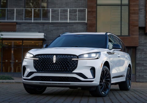 A 2026 Lincoln Aviator® Reserve model is shown with the available Jet Appearance Package parked near a restaurant. | Parks Lincoln of Wesley Chapel in Wesley Chapel FL