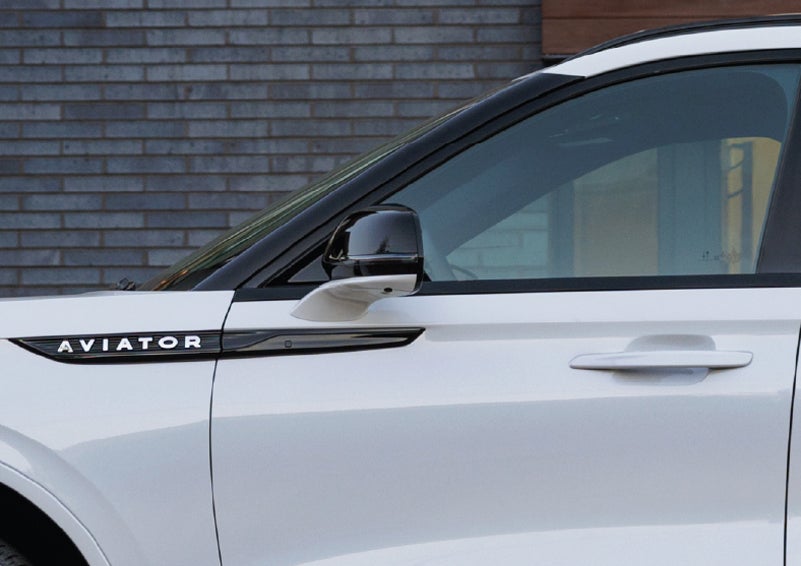 The driver’s side door and fender badging of a white 2026 Lincoln Aviator® SUV are showcased. | Parks Lincoln of Wesley Chapel in Wesley Chapel FL