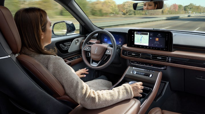 A 2026 Lincoln Aviator® SUV is being driven hands-free on a highway near a forest | Parks Lincoln of Wesley Chapel in Wesley Chapel FL