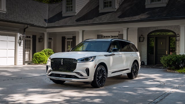 A white 2026 Lincoln Aviator® SUV is parked in the driveway of a luxury home. | Parks Lincoln of Wesley Chapel in Wesley Chapel FL