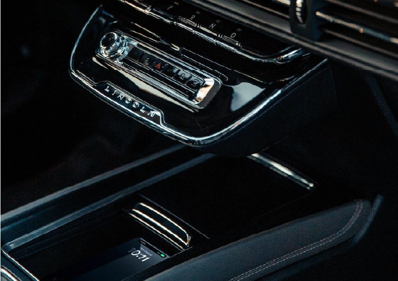 A smartphone rests on the available wireless charging pad in the front center console cubby. | Parks Lincoln of Wesley Chapel in Wesley Chapel FL