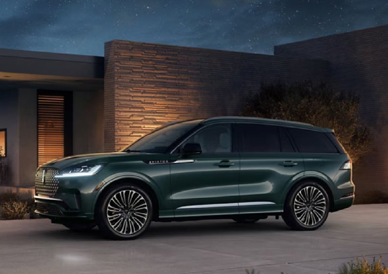 A green 2027 Lincoln Aviator® SUV is parked outside a contemporary home. | Parks Lincoln of Wesley Chapel in Wesley Chapel FL