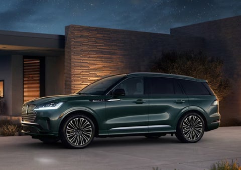 A green 2027 Lincoln Aviator® SUV is parked outside a contemporary home. | Parks Lincoln of Wesley Chapel in Wesley Chapel FL