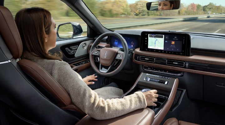 A 2027 Lincoln Aviator® SUV is being driven hands-free on a highway lined with trees. | Parks Lincoln of Wesley Chapel in Wesley Chapel FL