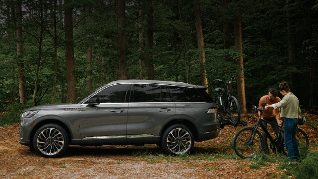 A father and son load e-bikes on a bike rack attached to a 2027 Lincoln Aviator® SUV. | Parks Lincoln of Wesley Chapel in Wesley Chapel FL
